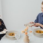 Two women dining with soup at an elegantly set table.