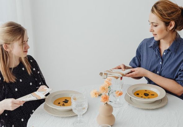 Two women dining with soup at an elegantly set table.